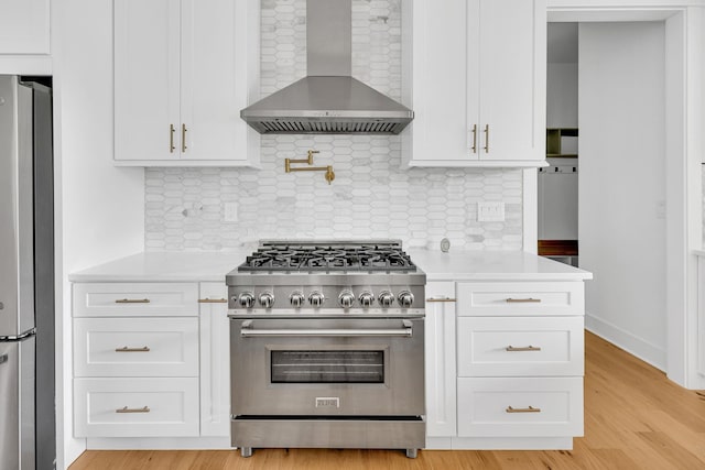164 Triangle Pine Rd, Fountain Inn, SC 29644 - kitchen with wall chimney exhaust hood, appliances with stainless steel finishes, light wood-type flooring, and white cabinetry