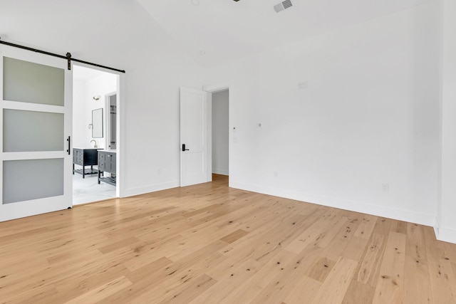 164 Triangle Pine Rd, Fountain Inn, SC 29644 - unfurnished bedroom with light wood finished floors, a barn door, high vaulted ceiling, and connected bathroom