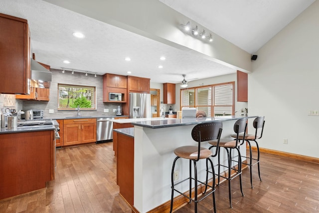 116 Dorothy Ln, Pickens, SC 29671 - kitchen featuring stainless steel appliances, wall chimney exhaust hood, light wood-style flooring, a breakfast bar, and decorative backsplash