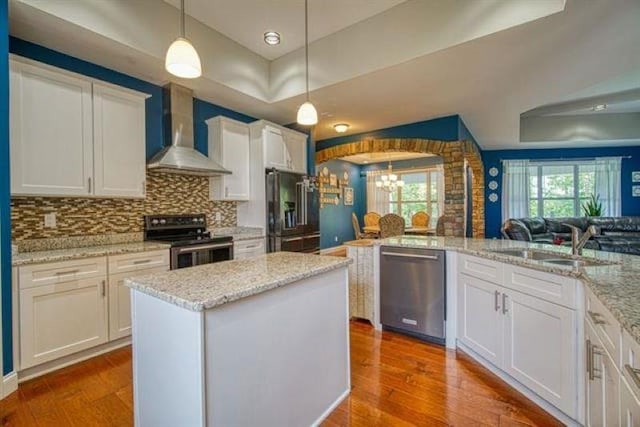 217 Aqua Cove Ct, Inman, SC 29349 - kitchen featuring appliances with stainless steel finishes, wall chimney range hood, a chandelier, arched walkways, and dark wood-style floors