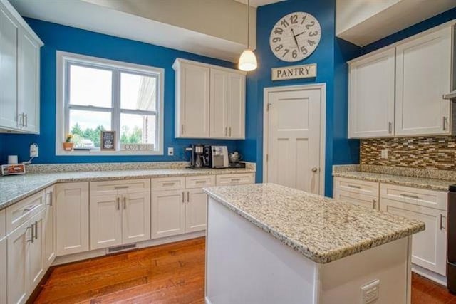 217 Aqua Cove Ct, Inman, SC 29349 - kitchen featuring wood finished floors, a center island, hanging light fixtures, and white cabinetry
