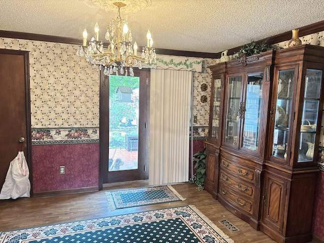 8627 Valley Falls Rd, Boiling Springs, SC 29316 - doorway featuring a textured ceiling, a chandelier, wood finished floors, crown molding, and wallpapered walls