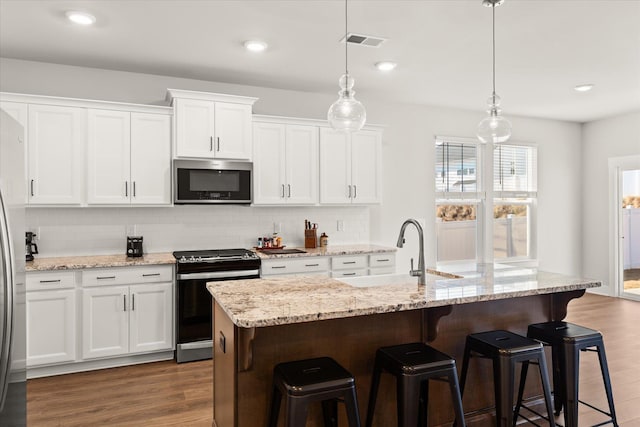 424 Granbury Dr, Duncan, SC 29334 - kitchen with appliances with stainless steel finishes, tasteful backsplash, white cabinets, a kitchen bar, and dark wood-type flooring