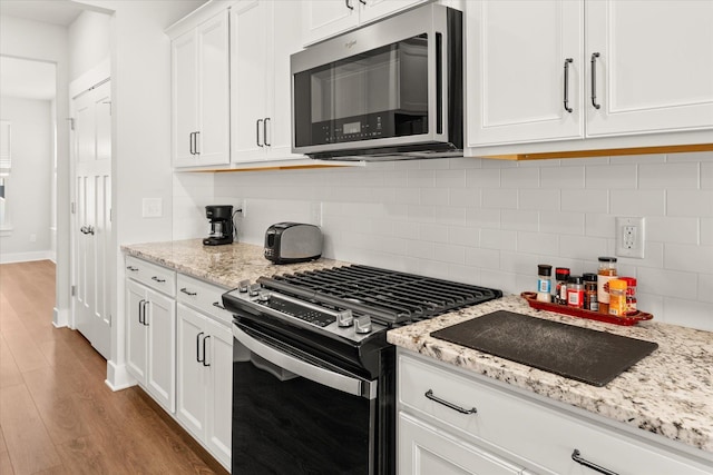 424 Granbury Dr, Duncan, SC 29334 - kitchen with stainless steel appliances, white cabinetry, light wood-style floors, backsplash, and light stone counters