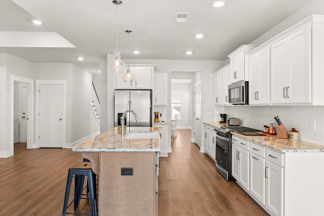 424 Granbury Dr, Duncan, SC 29334 - kitchen with appliances with stainless steel finishes, wood finished floors, a center island with sink, recessed lighting, and white cabinets