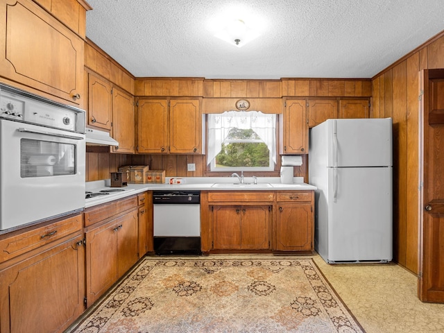1310 Mount Zion Rd, Spartanburg, SC 29303 - kitchen featuring white appliances, brown cabinetry, a textured ceiling, under cabinet range hood, and light countertops