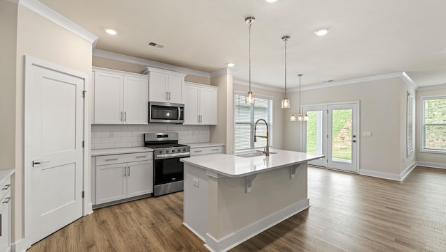 310 Fiery Rd, Mauldin, SC 29607 - kitchen featuring appliances with stainless steel finishes, ornamental molding, dark wood finished floors, light countertops, and a kitchen island with sink