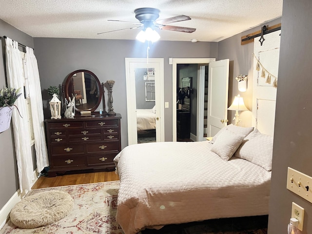 510 E Earle St, Landrum, SC 29356 - bedroom with a barn door, wood finished floors, a textured ceiling, and ceiling fan