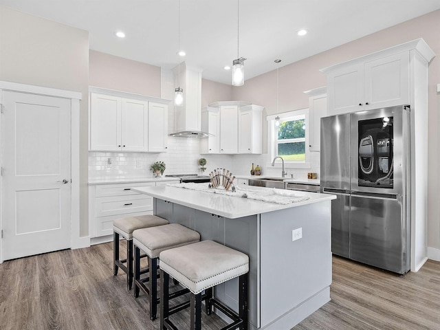 433 Josie Way, Boiling Springs, SC 29316 - kitchen featuring smart refrigerator, wall chimney range hood, a kitchen island, wood finished floors, and white cabinetry