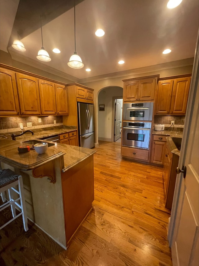 204 Tuscan Ridge Trl, Inman, SC 29349 - kitchen with stainless steel appliances, arched walkways, ornamental molding, a peninsula, and brown cabinets