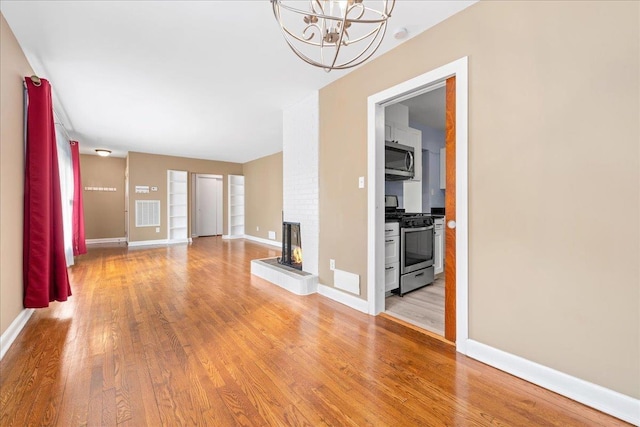 222 Woodview Ave, Spartanburg, SC 29306 - unfurnished living room featuring light wood-type flooring, a fireplace, and a chandelier