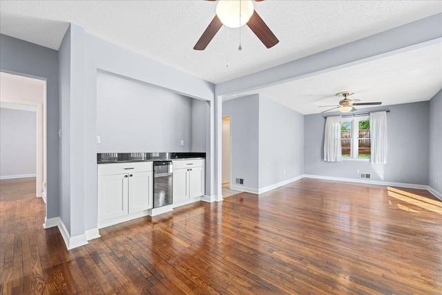 222 Woodview Ave, Spartanburg, SC 29306 - unfurnished living room featuring a ceiling fan, wine cooler, dark wood-type flooring, bar, and a textured ceiling