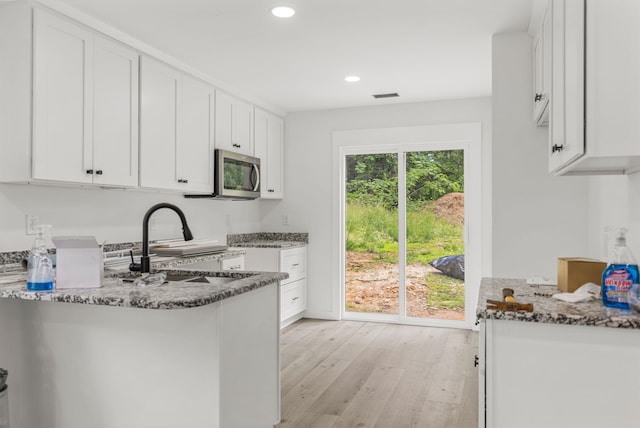 139 Carolina Ave, Spartanburg, SC 29306 - kitchen featuring stainless steel microwave, stone counters, light wood-style floors, white cabinetry, and recessed lighting