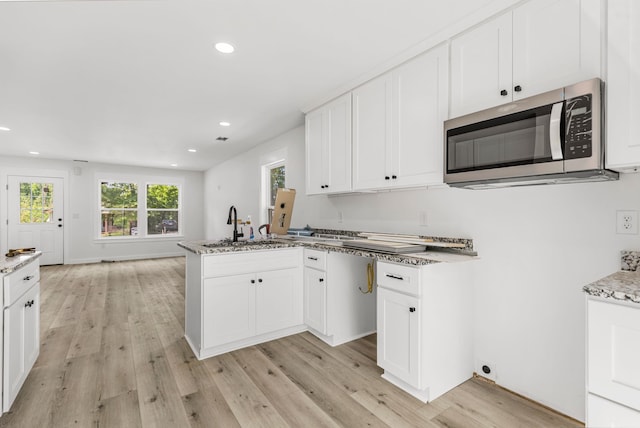 139 Carolina Ave, Spartanburg, SC 29306 - kitchen featuring stainless steel microwave, a peninsula, light wood-style floors, recessed lighting, and light stone countertops