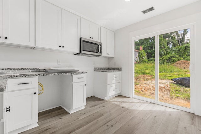 139 Carolina Ave, Spartanburg, SC 29306 - kitchen featuring stainless steel microwave, light wood-style flooring, white cabinetry, and light stone counters