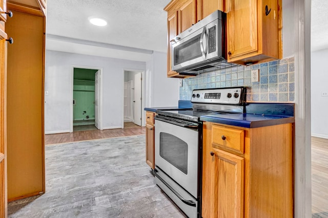 211 Skyline Rd, Greer, SC 29651 - kitchen with stainless steel appliances, dark countertops, backsplash, light wood-style floors, and brown cabinets