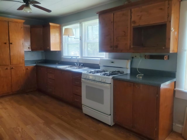 190 Beaverdam Church Rd, Enoree, SC 29335 - kitchen featuring white range with gas cooktop, a ceiling fan, light wood-style flooring, brown cabinets, and dark countertops