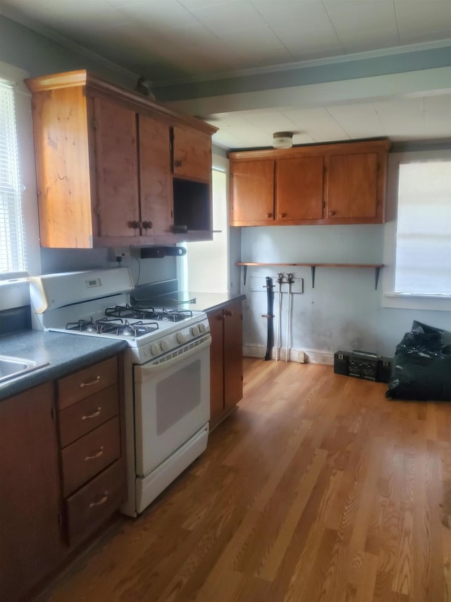190 Beaverdam Church Rd, Enoree, SC 29335 - kitchen featuring white gas stove, ornamental molding, wood finished floors, healthy amount of natural light, and brown cabinets