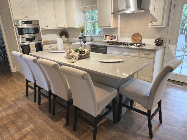 155 Lake Park Dr, Spartanburg, SC 29301 - kitchen with wall chimney exhaust hood, stainless steel appliances, dark wood-style flooring, and a breakfast bar
