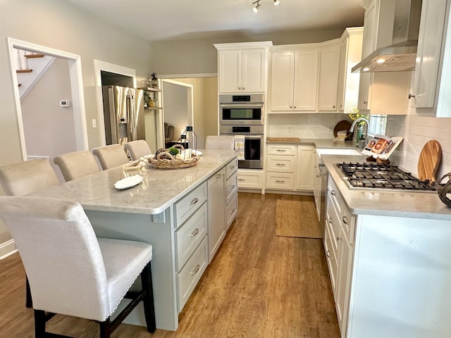 155 Lake Park Dr, Spartanburg, SC 29301 - kitchen with wall chimney range hood, appliances with stainless steel finishes, a kitchen breakfast bar, and white cabinetry