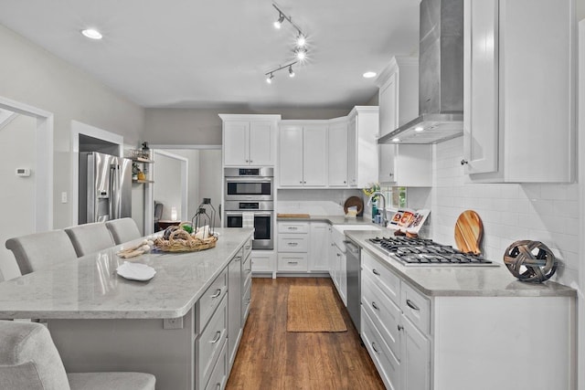 155 Lake Park Dr, Spartanburg, SC 29301 - kitchen with wall chimney exhaust hood, appliances with stainless steel finishes, a breakfast bar, white cabinetry, and recessed lighting