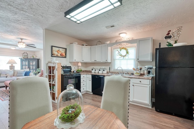 1762 New Cut Rd, Spartanburg, SC 29303 - kitchen with black appliances, a textured ceiling, light wood-type flooring, light countertops, and white cabinetry