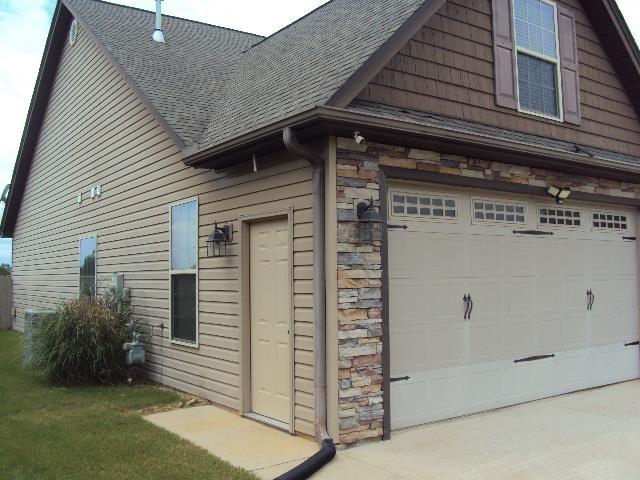 108 Dewfield Ln, Boiling Springs, SC 29316 - view of side of property with roof with shingles, stone siding, an attached garage, and concrete driveway