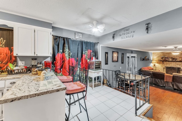 125 Greenway Ave, Union, SC 29379 - kitchen featuring ceiling fan, white cabinetry, a fireplace, light stone countertops, and a textured ceiling