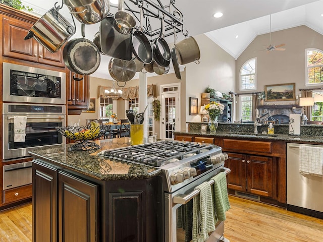 458 Carolina Club Dr, Spartanburg, SC 29306 - kitchen with appliances with stainless steel finishes, a warming drawer, vaulted ceiling, a kitchen island, and light wood-type flooring