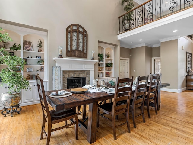 458 Carolina Club Dr, Spartanburg, SC 29306 - dining area with light wood finished floors, built in shelves, a high ceiling, a fireplace, and crown molding