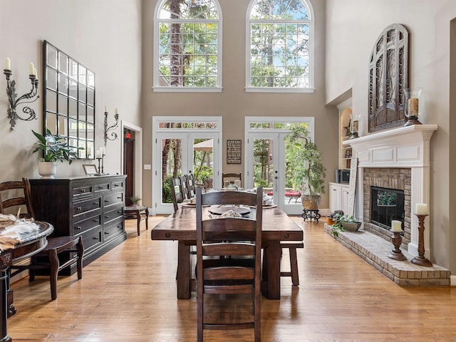 458 Carolina Club Dr, Spartanburg, SC 29306 - dining room with french doors, a high ceiling, plenty of natural light, light wood-style flooring, and a brick fireplace