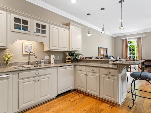 458 Carolina Club Dr, Spartanburg, SC 29306 - kitchen featuring ornamental molding, a breakfast bar area, a peninsula, light wood-style flooring, and white cabinets