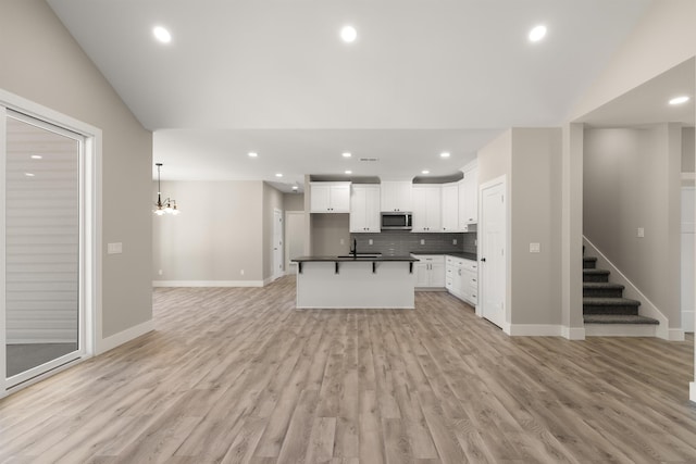 3135 E Croft Cir, Spartanburg, SC 29302 - kitchen with dark countertops, stainless steel microwave, open floor plan, backsplash, and light wood-type flooring