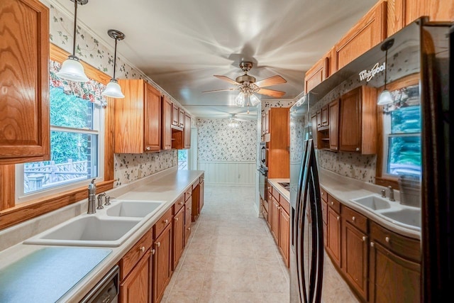 2250 Hickory Dr, Spartanburg, SC 29302 - kitchen featuring wallpapered walls, ceiling fan, brown cabinetry, wainscoting, and decorative light fixtures