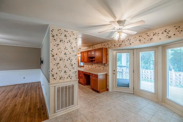 2250 Hickory Dr, Spartanburg, SC 29302 - kitchen with brown cabinetry, crown molding, healthy amount of natural light, light countertops, and a ceiling fan