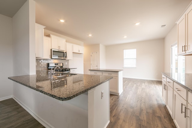1262 Elterwater Ln, Spartanburg, SC 29306 - kitchen with appliances with stainless steel finishes, dark wood-style floors, a peninsula, dark stone countertops, and white cabinets