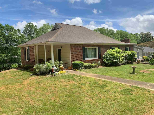 107 S Poplar Ave, Landrum, SC 29356 - view of front of house with a front yard, brick siding, a chimney, and roof with shingles