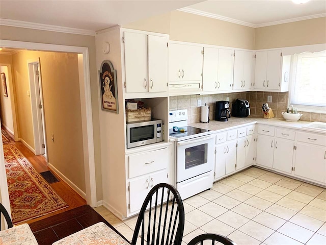 107 S Poplar Ave, Landrum, SC 29356 - kitchen featuring white range with electric stovetop, stainless steel microwave, under cabinet range hood, decorative backsplash, and light countertops