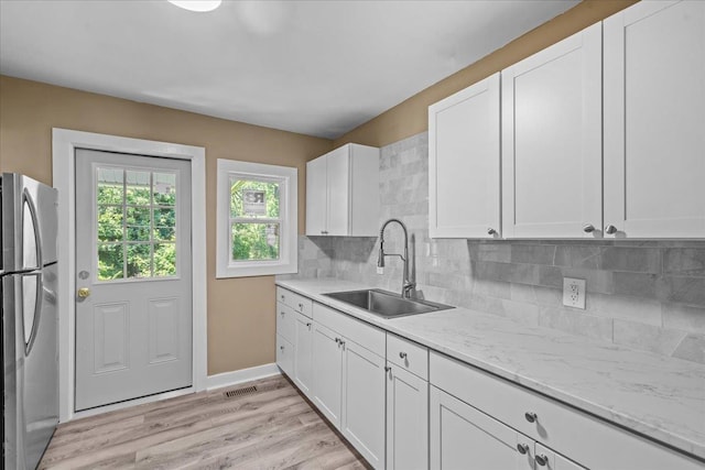 504 Hilda St, Spartanburg, SC 29306 - kitchen with freestanding refrigerator, backsplash, white cabinetry, and light wood finished floors