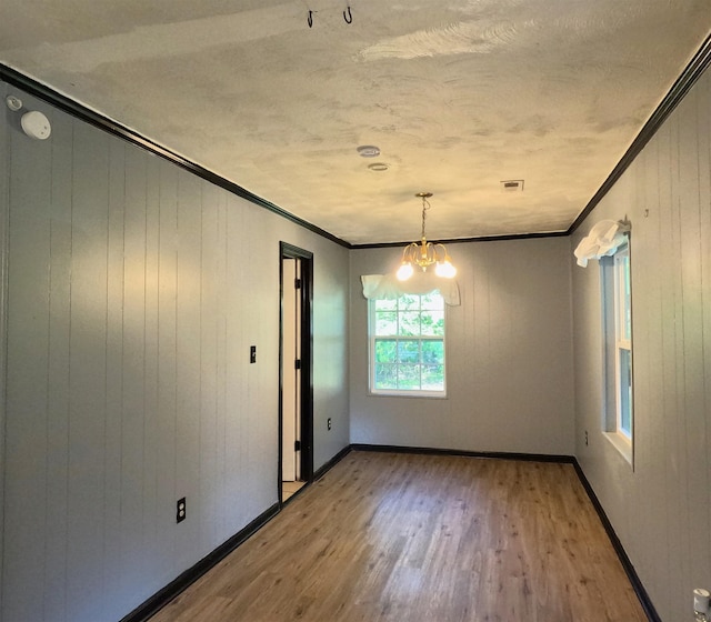 105 Anderson St, Spartanburg, SC 29301 - unfurnished dining area featuring crown molding, wood finished floors, a chandelier, a textured ceiling, and wooden walls