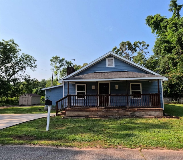 105 Anderson St, Spartanburg, SC 29301 - view of front facade featuring covered porch, a storage shed, a chimney, a front yard, and a shingled roof