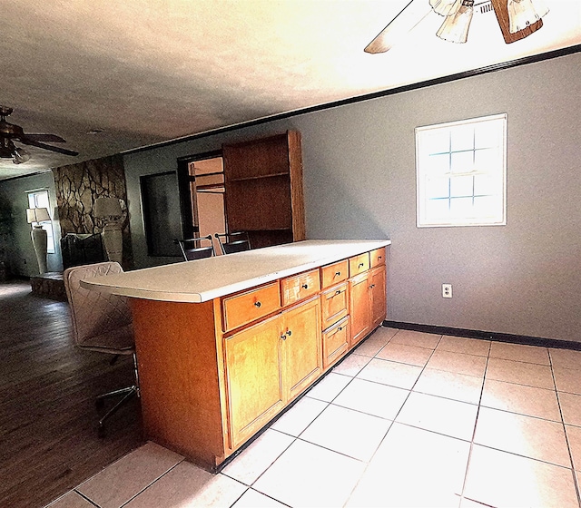 105 Anderson St, Spartanburg, SC 29301 - kitchen featuring ceiling fan, brown cabinets, a peninsula, light countertops, and a kitchen breakfast bar