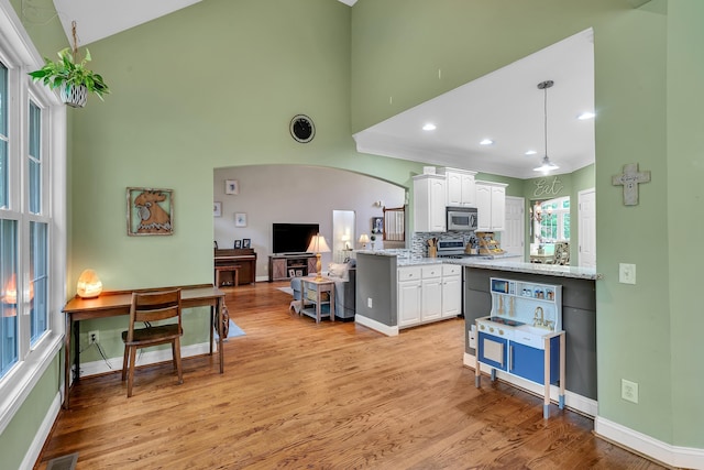 2030 Fasana Rd, York, SC 29745 - kitchen featuring stainless steel microwave, white cabinets, arched walkways, light wood-type flooring, and high vaulted ceiling