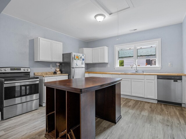24 Oak St, Spartanburg, SC 29306 - kitchen featuring appliances with stainless steel finishes, wooden counters, light wood-type flooring, a kitchen island, and white cabinets