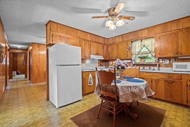195 Seigle Dr, Inman, SC 29349 - kitchen with white appliances, wood walls, light flooring, brown cabinets, and a textured ceiling