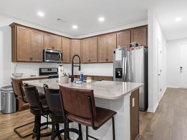 115 Turfway Dr, Greer, SC 29651 - kitchen with appliances with stainless steel finishes, wood finished floors, light stone countertops, recessed lighting, and a center island with sink