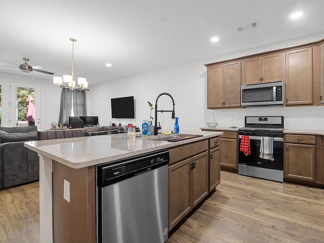 115 Turfway Dr, Greer, SC 29651 - kitchen featuring stainless steel appliances, open floor plan, light wood-type flooring, backsplash, and a center island with sink