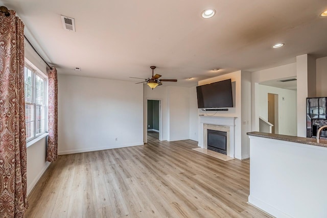 811 S Edisto River Dr, Roebuck, SC 29376 - unfurnished living room featuring light wood-style flooring, a ceiling fan, recessed lighting, and a fireplace with flush hearth