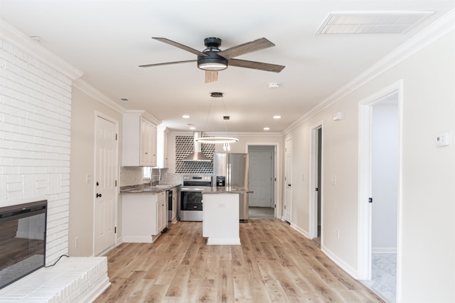 1230 Edgewood Ave, Spartanburg, SC 29301 - kitchen with appliances with stainless steel finishes, wall chimney exhaust hood, white cabinets, a kitchen island, and ornamental molding