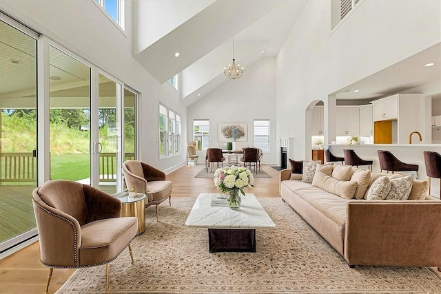 740 Enoree River Pl, Greer, SC 29651 - living room featuring a high ceiling, light wood-type flooring, arched walkways, a chandelier, and a baseboard radiator